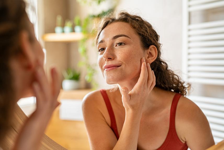 Woman looking at acne on face