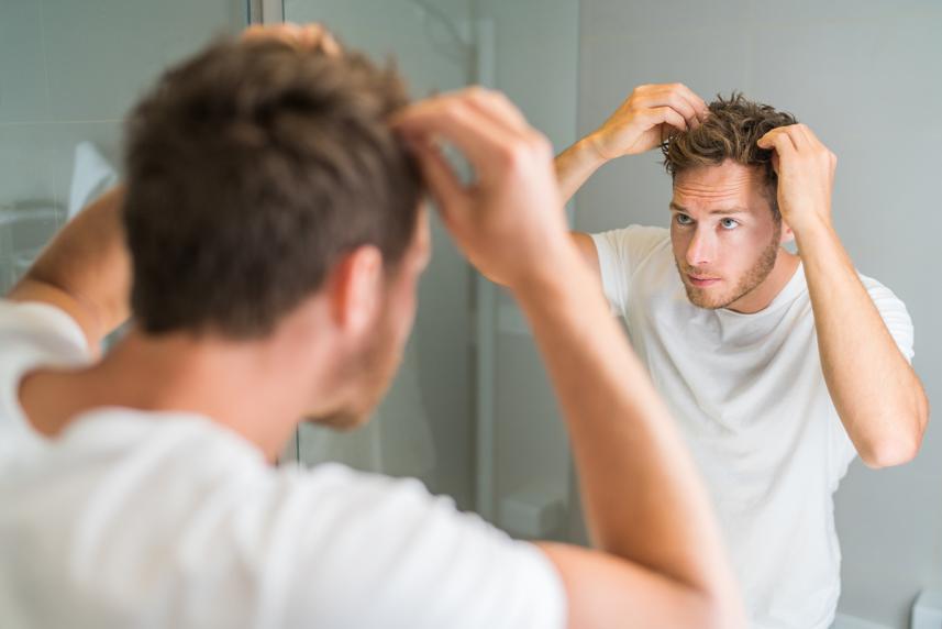 Person checking for hair loss in front of the mirror