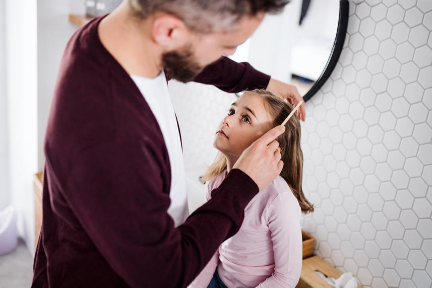 Person checking for head lice on their daughters hair