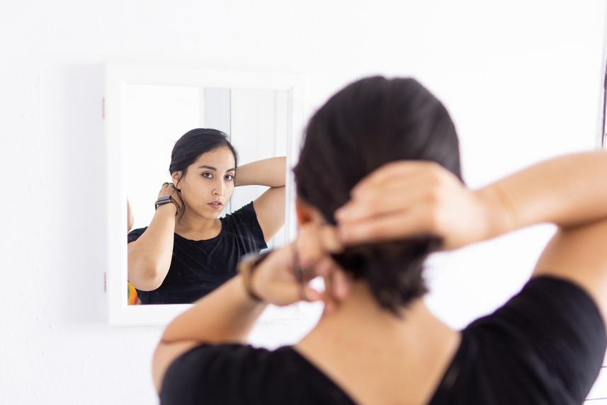 Woman tying her hair in front of a mirror