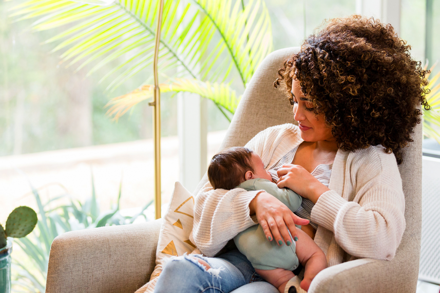 Woman breastfeeding her newborn for an article on breastfeeding supplies