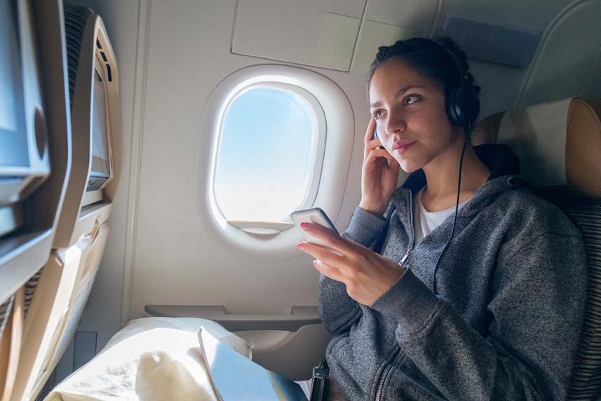 Woman on an airplane with headphones on  