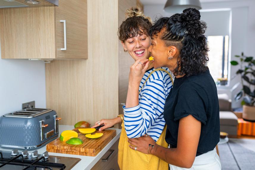 Smiling woman feeding another woman fruit