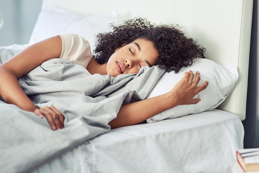 Woman lying in bed for an article on technology and devices that improve sleep
