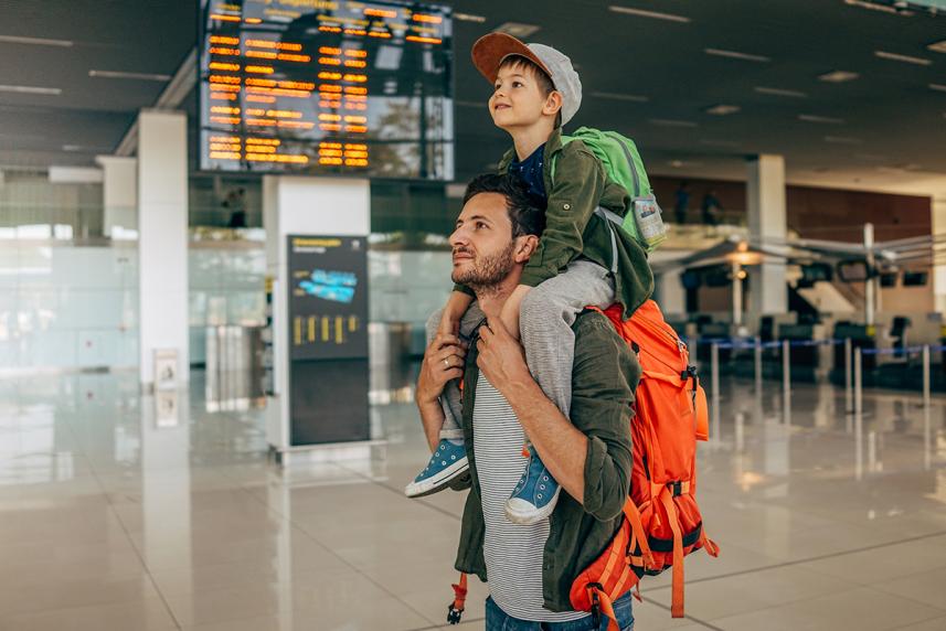 Boy sitting on his father's shoulder in an airport