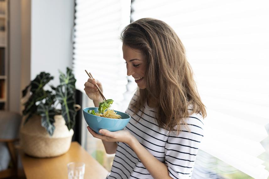 A woman eating a healthy homemade bowl of noodles