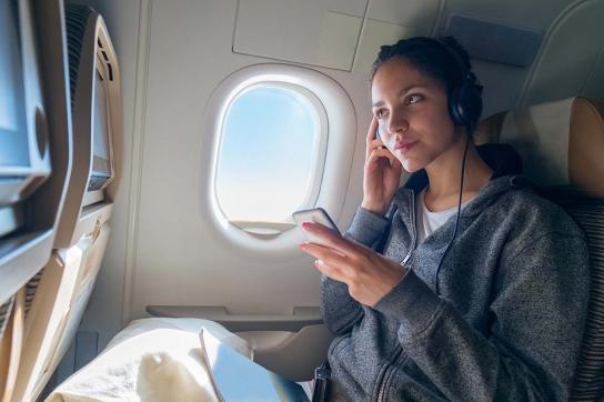 Woman on an airplane with headphones on  